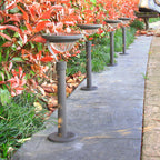 Arc solar garden lights beside a path in daylight; sold individually